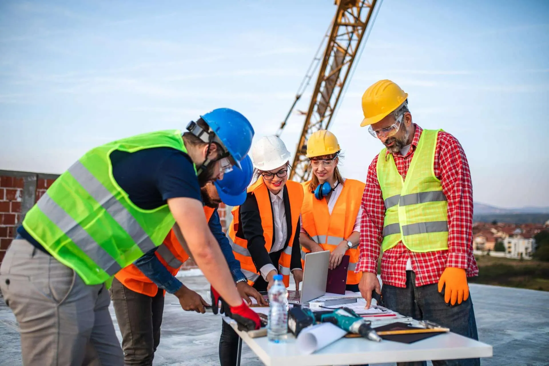 Construction professionals reviewing plans beside active heavy equipment